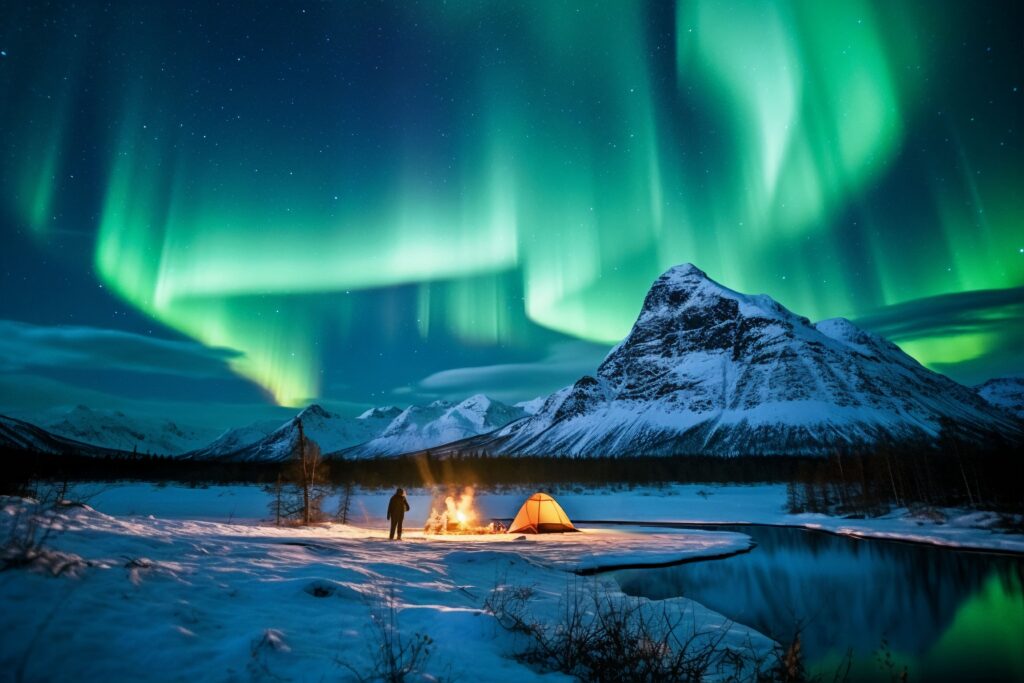 Aurora boreal aparece enquanto um senhor acampa no meio de uma montanha cheia de neve